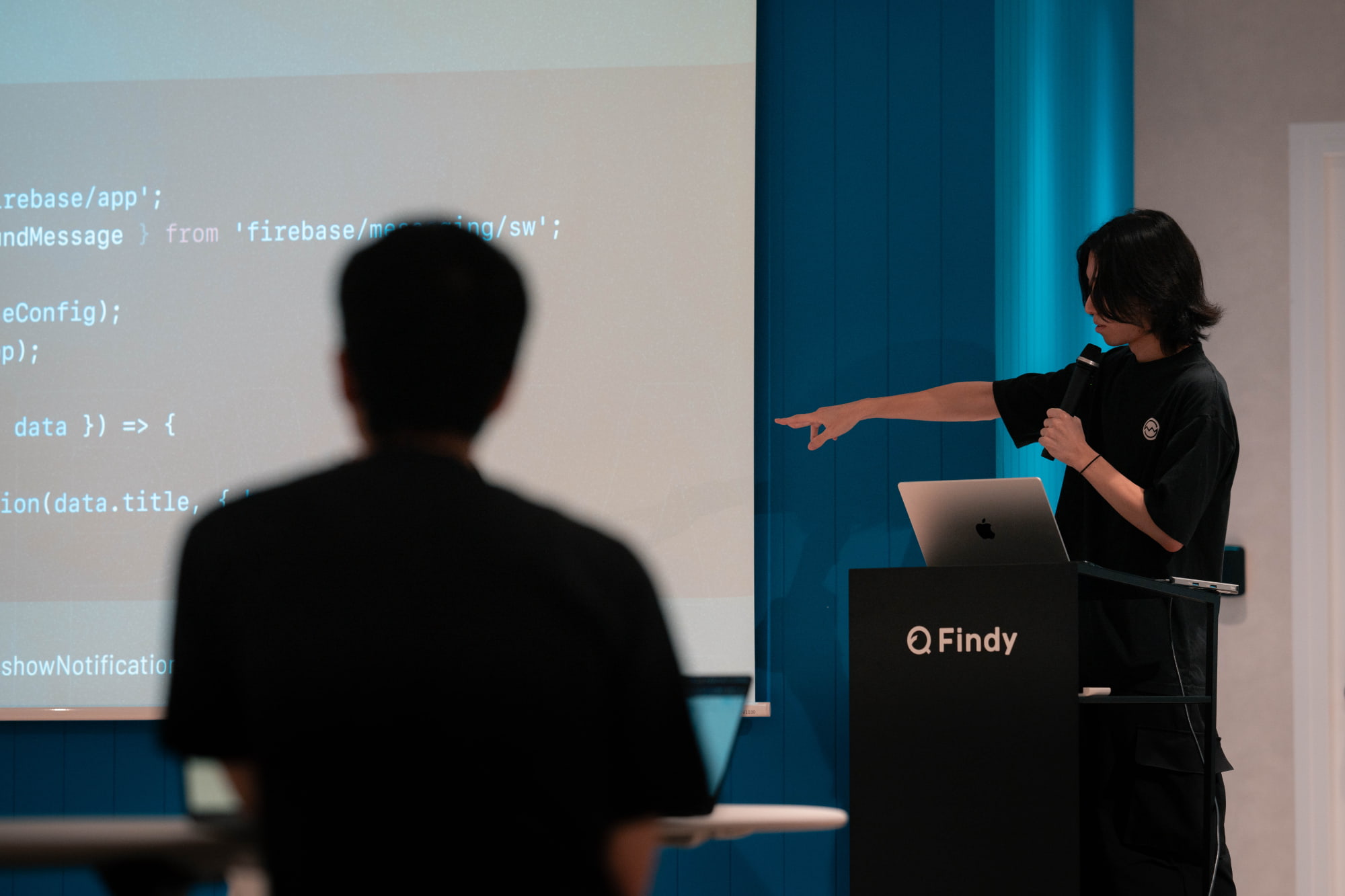 登壇中の様子。スクリーンには firebase/messaging/sw のコードが映っている
