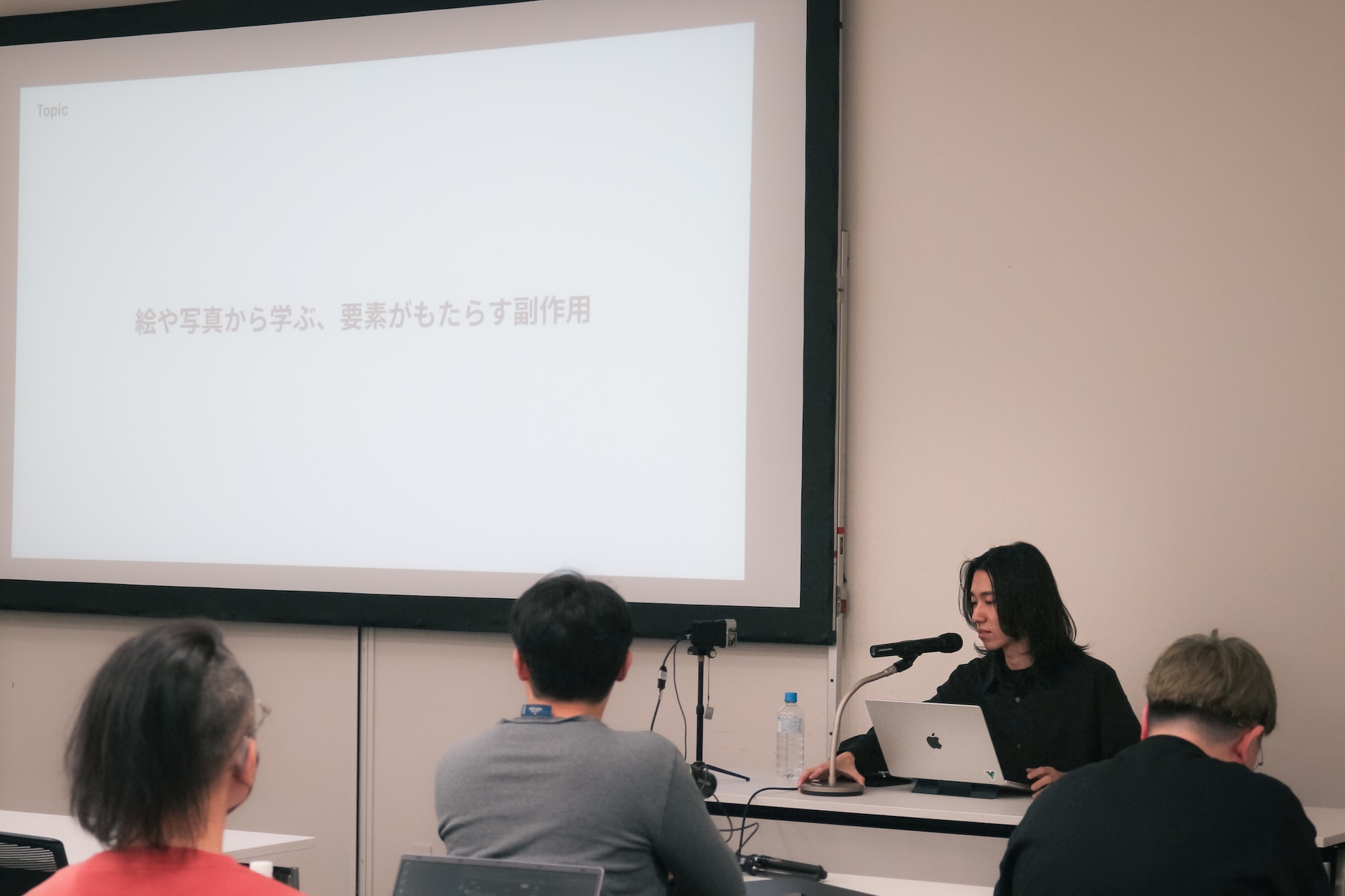 DIST.53「スライドデザイン道場」での登壇の様子。スクリーンには『絵や写真から学ぶ、要素がもたらす副作用』のタイトルスライドが表示されている